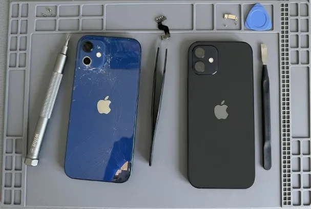 Un iPhone 12 à la vitre arrière brisée à côté d'un iPhone 12 réparé, entourés d'outils de précision sur un tapis d'atelier